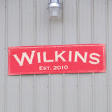 Family name Metal Sign - WIlkins, Established 2010 located in New Palestine, Indiana. Hung from large garage.